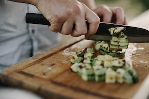 Koch schneidet Zucchini auf einem Brett