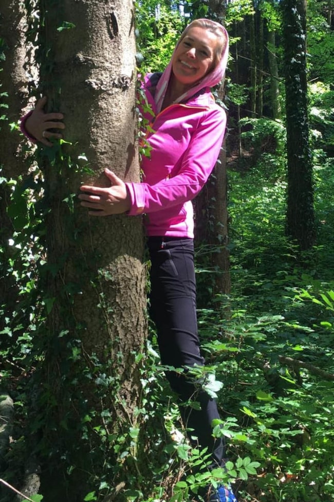Frau umarmt einen Baum im Wald