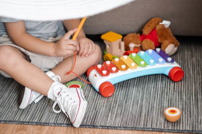 Kleinkind sitzt am Boden und spielt mit Spielzeug