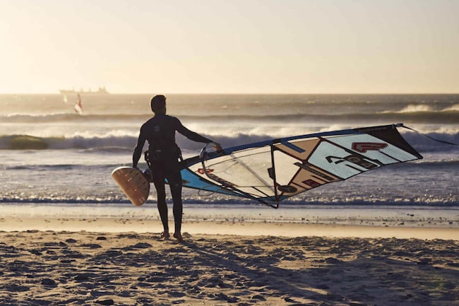 Surfer trägt sein Board am Strand zum Meer