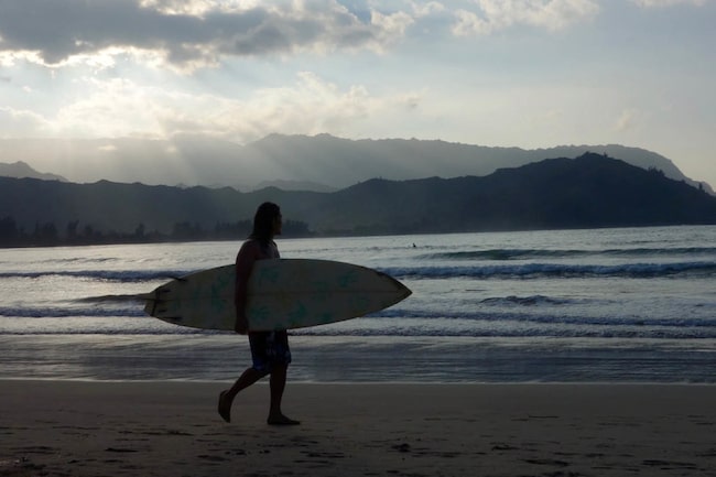 Surfer spaziert bei Sonnenuntergang am Strand