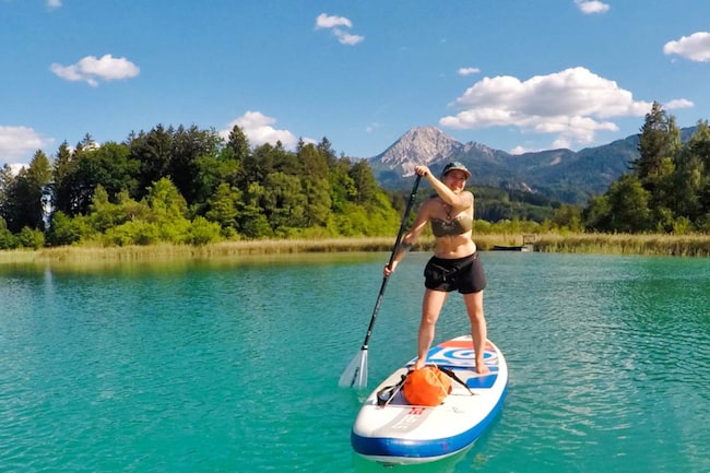 Frau paddelt am See mit Stand Up Paddle