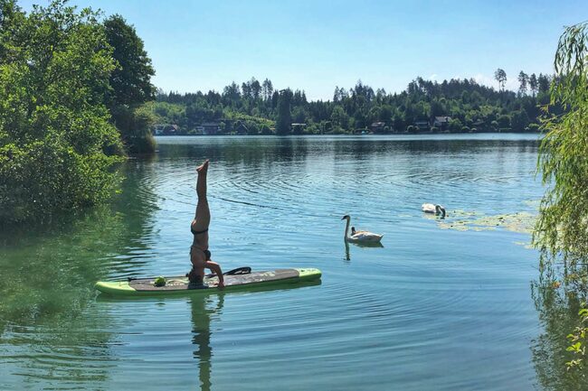 Stand Up Paddling Frau mach einen Handstand im Wasser am Brett