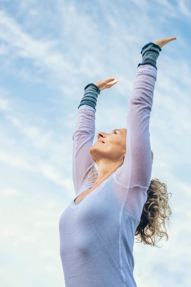Zufriedene Frau streckt die Arme für Yoga in die Luft