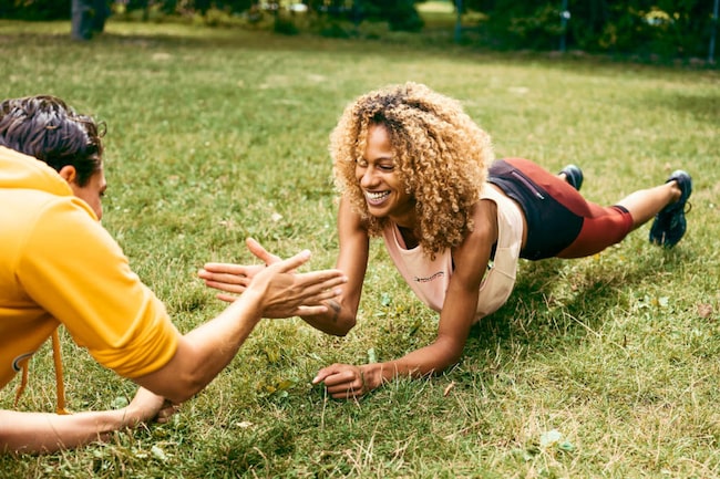 Outdoor Training am Spielplatz: Mann und Frau machen eine Turnübung in der Wiese