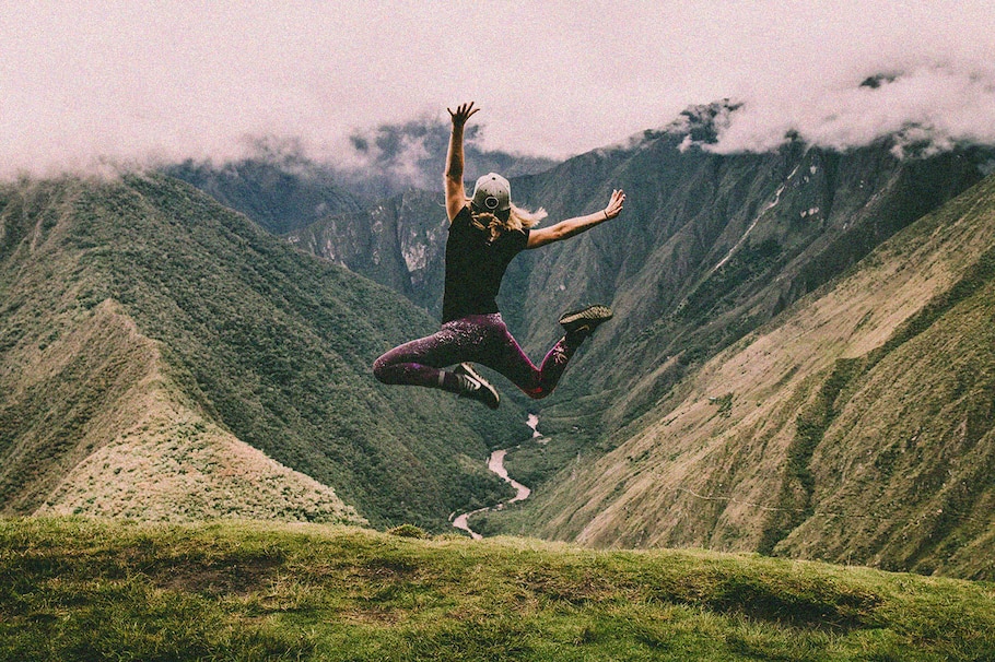 Frau springt bei Bergsteigen in die Luft