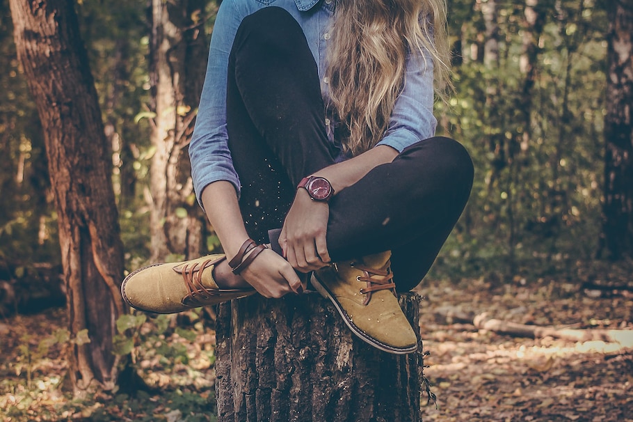 Frau sitzt auf Baumstamm im Herbstwald