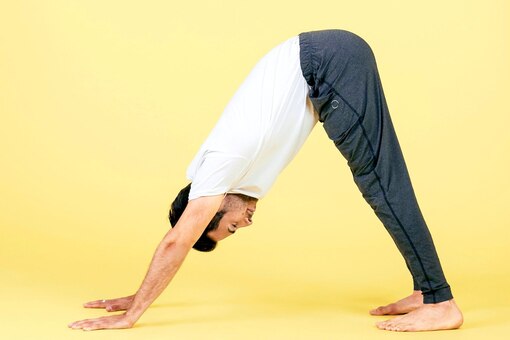 herabschauender Hund, Yogaposition, Mann, gelber Hintergrund