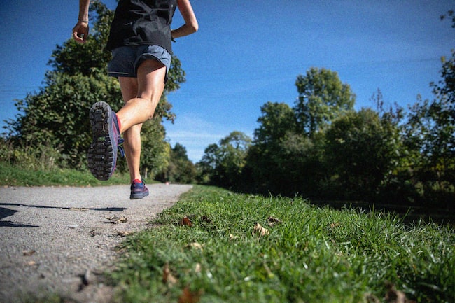 Mann joggt neben Wiese