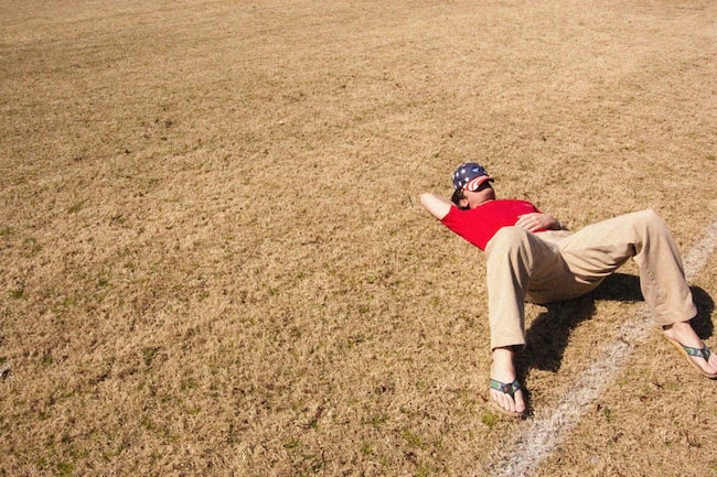 Mann liegt faul auf Feld