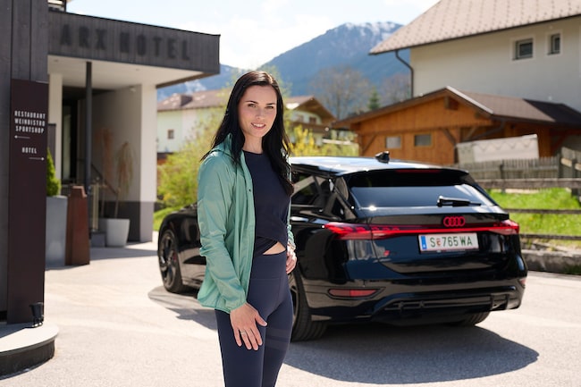 Anna Veith und ihr Audi stehen vor einem Hotel, sie sind am Ziel ihrer Fahrt angekommen.