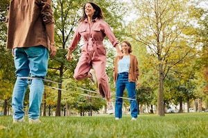 zwei Frauen, ein Mann, Park, Wiese, Bäume, Herbst, Gummihüpfen, Outdoorspiele, Bewegung, Sport, Spaß, carpe diem