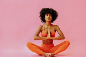Frau, orange Sportkleidung, Yoga, Yogapose, rosa Hintergrund