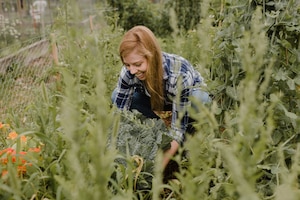 junge Frau, üppig gewachsener Gemüsegarten, Sommer, Gartenarbeiten