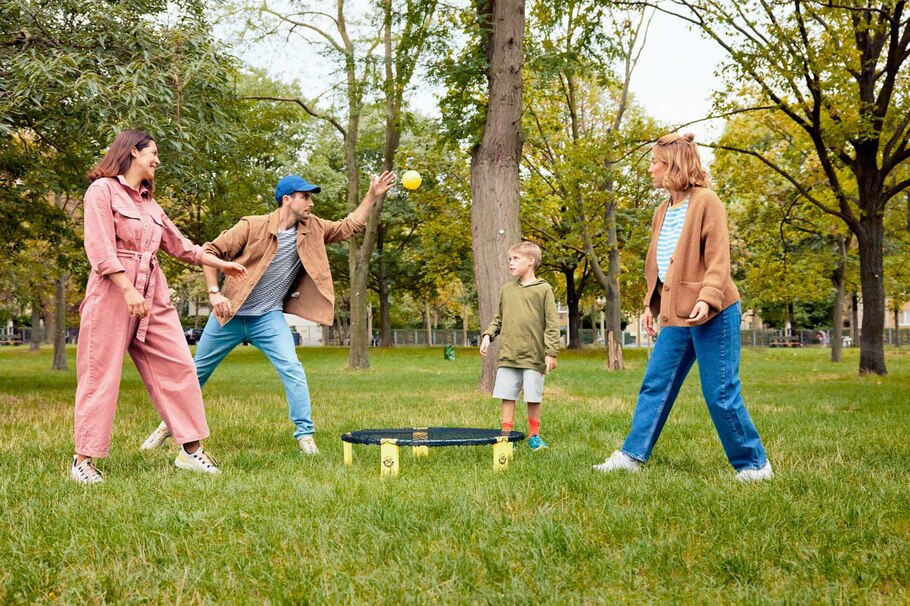 zwei Frauen, ein Mann, ein Kind, Junge, Bub, Spikeball spielen, Ball, Netz, Park, Wiese, Bäume, Bewegung, Spiel, carpe diem