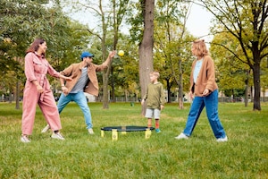 zwei Frauen, ein Mann, ein Kind, Junge, Bub, Spikeball spielen, Ball, Netz, Park, Wiese, Bäume, Bewegung, Spiel, carpe diem