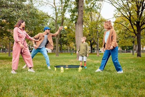 zwei Frauen, ein Mann, ein Kind, Junge, Bub, Spikeball spielen, Ball, Netz, Park, Wiese, Bäume, Bewegung, Spiel, carpe diem