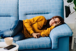 Powernap, schlafende Frau am Sofa, blaues Sofa, Wohnzimmer