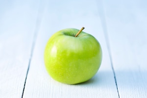 Grüner Apfel auf weißem Holzboden