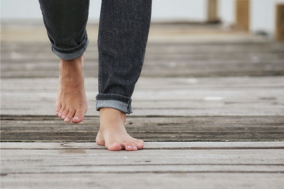Barfuß gehen hat viele Vorteile: Männerfüße barfuß auf Holzplanken draußen