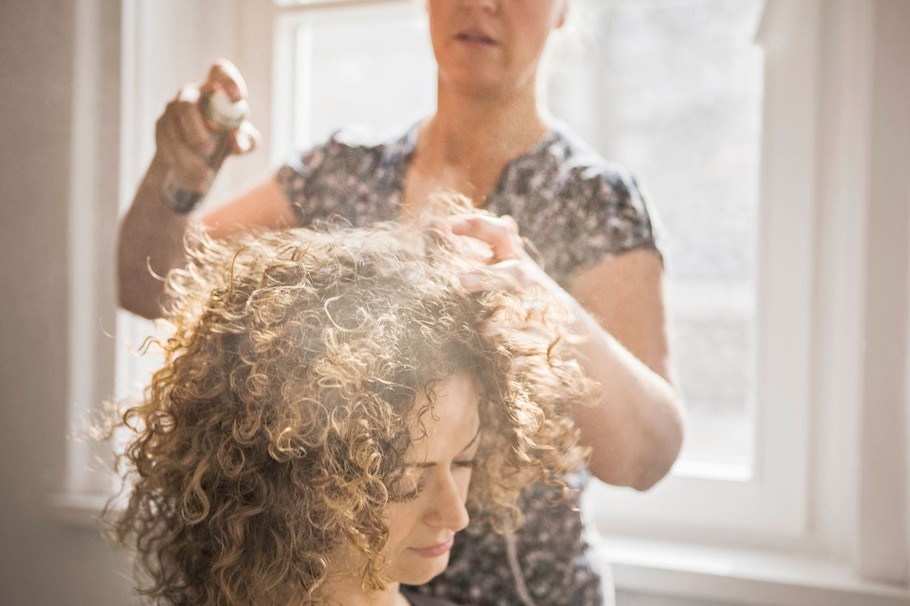 Haare ab oder lieber nicht: Frau mit Locken wird mit Haarspray gestylt