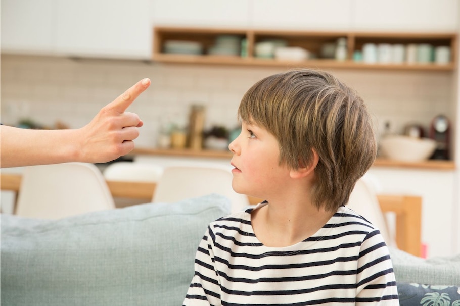 Zeigefinger droht Kind auf Sofa - weniger schimpfen wäre besser