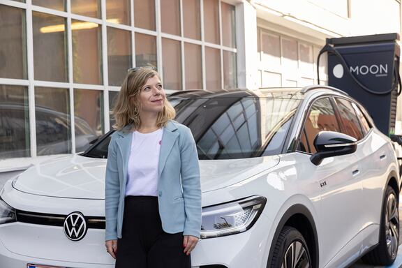 Sissi Volger steht vor einer MOON-Ladesäule und ihrem VW ID.4