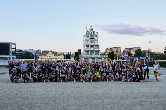 Viele Läuferinnen und Läufer des POWER RUN stehen gemeinsam für ein Gruppenfoto zusammen und halten ihre Hände in die Höhe.