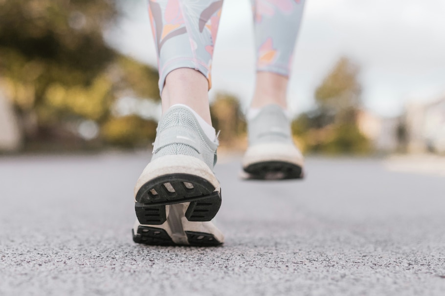 Zwei Paar Laufschuhe auf Asphalt, die eine laufende Bewegung nachahmen.