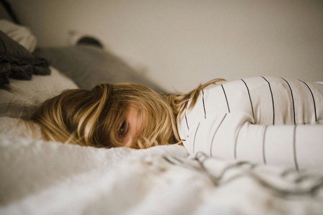 Frau auf Bett, offenes Augen, Haare im Gesicht