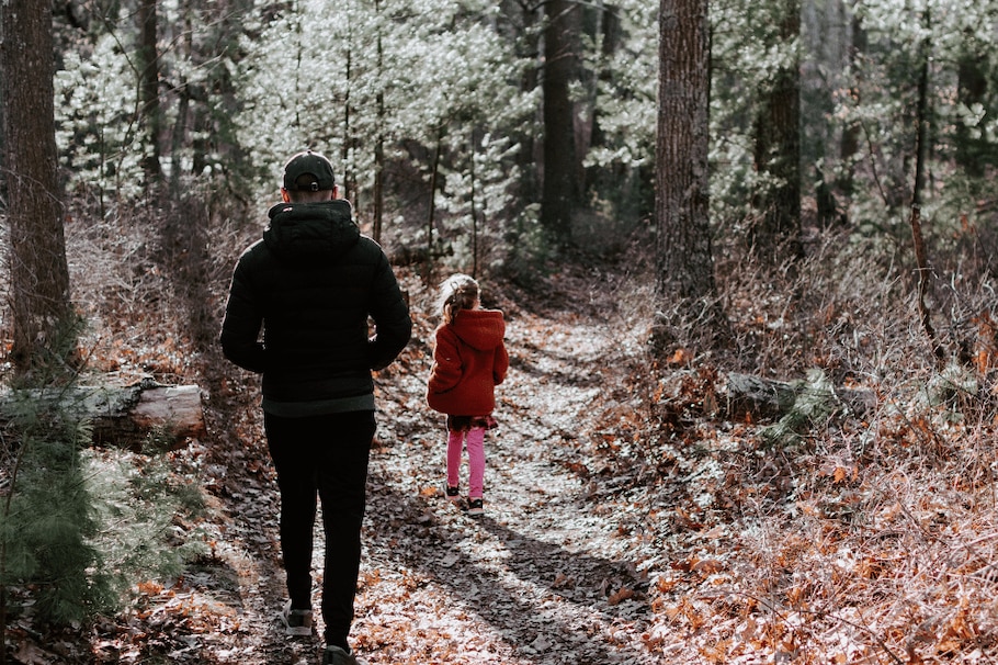 Mann und Kind spazieren in herbstlichem Wald