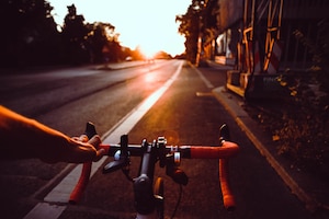 Mann fährt Fahrrad Richtung Sonnenuntergang