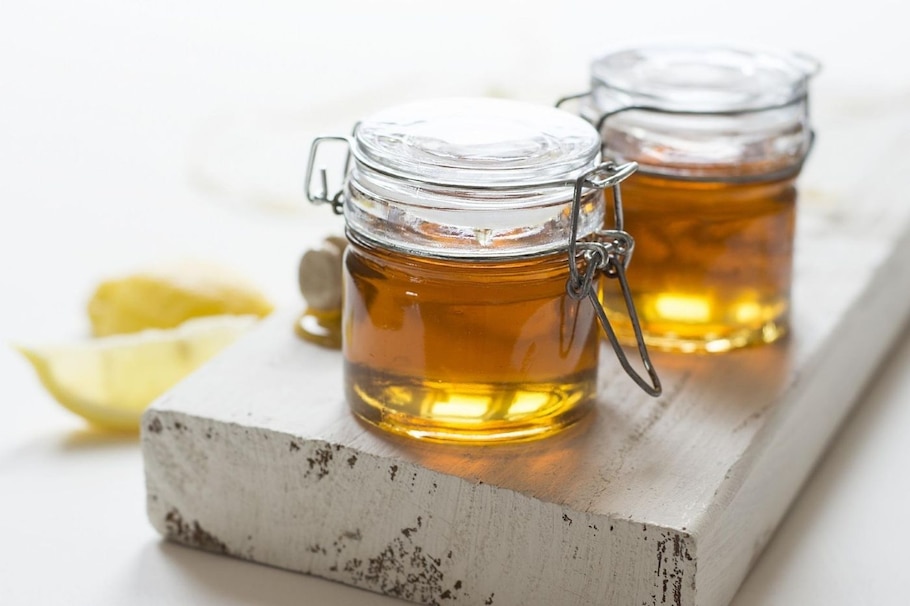 Honig ist gesund: Flüssiger goldgelber Honig in Gläsern auf weißem Brett