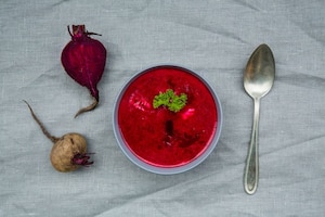 Topshot von Rote-Rüben-Suppe mit Löffel und Rote-Rüben-Knolle