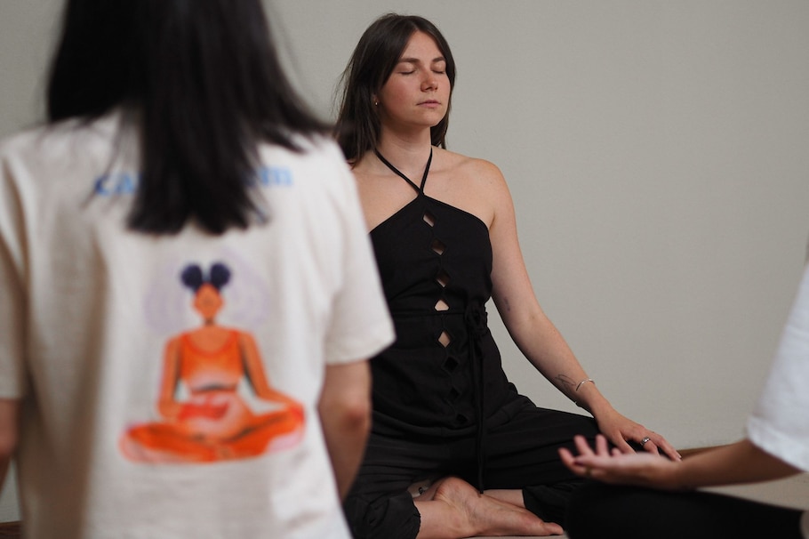 Breathwork Trainerin Julia Freidl sitzt im Schneidersitz und leitet eine Gruppe durch eine Atemübung