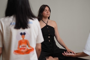 Breathwork Trainerin Julia Freidl sitzt im Schneidersitz und leitet eine Gruppe durch eine Atemübung