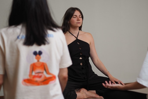 Breathwork Trainerin Julia Freidl sitzt im Schneidersitz und leitet eine Gruppe durch eine Atemübung