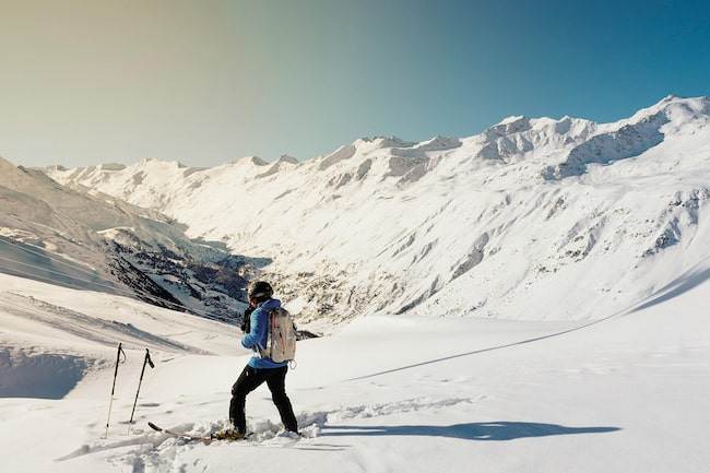 Ein Skifahrer mitten in schneebedeckter Berglandschaft legt eine kurze Pause ein.