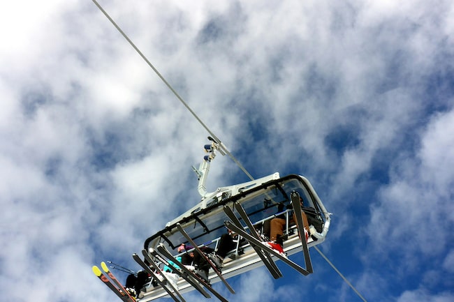 Ein achtsitziger Sessellift mit Skifahrern, die unterwegs zur Bergstation sind.