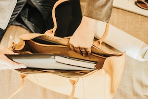 Eine Frau bereitet ihre Arbeitstasche vor und steckt ein Notizbuch ein.