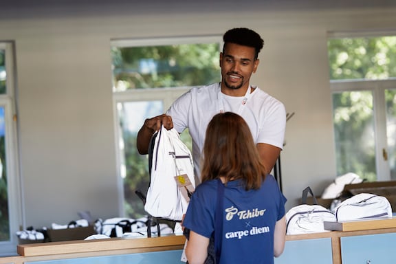 Ein Mann übergibt einer Teilnehmerin die Goodie-Bag des POWER RUN.