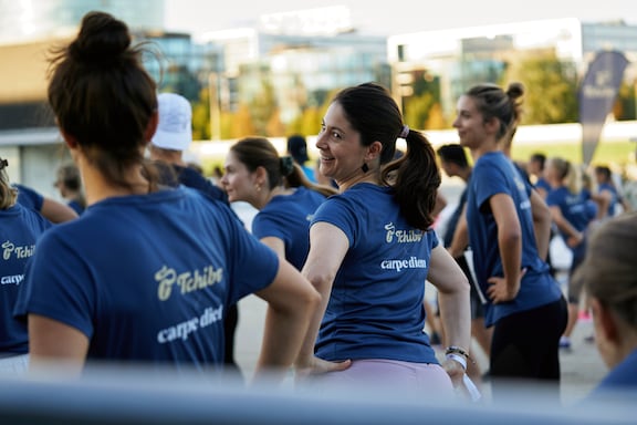 Eine Teilnehmerin des POWER RUN dreht sich beim Aufwärmen zu ihrer Freundin um.