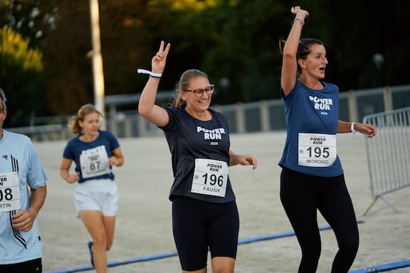 Teilnehmerinnen des POWER RUN überqueren die Ziellinie und freuen sich.