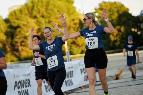 Teilnehmerinnen des POWER RUN überqueren die Ziellinie und freuen sich.
