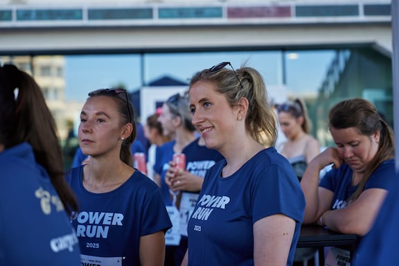 Teilnehmerinnen des POWER RUN hören aufmerksam der Moderation zu.