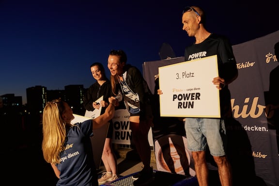 Eine Tchibo Mitarbeiterin gratuliert der Siegerin des POWER RUN.