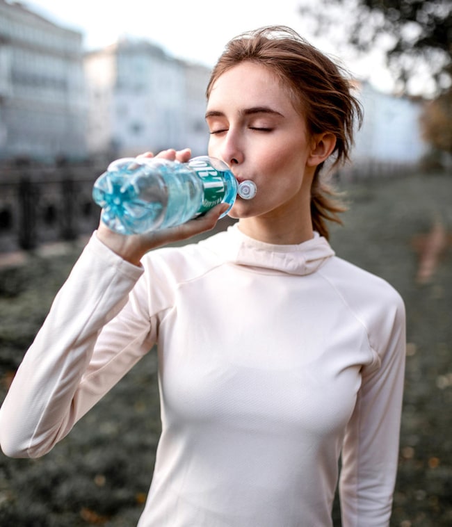 Eine Frau trinkt aus einer Vöslauer Flasche.